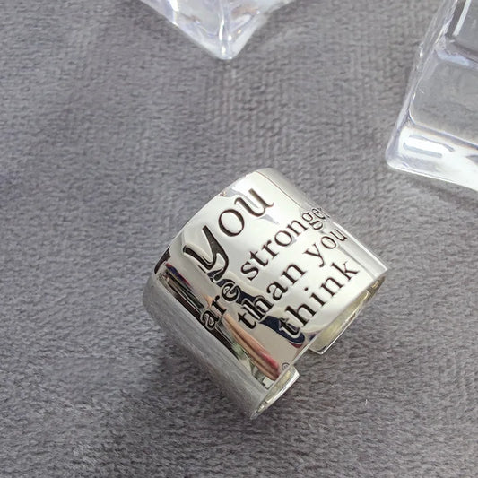 Silver charm with engraved text on a gray surface